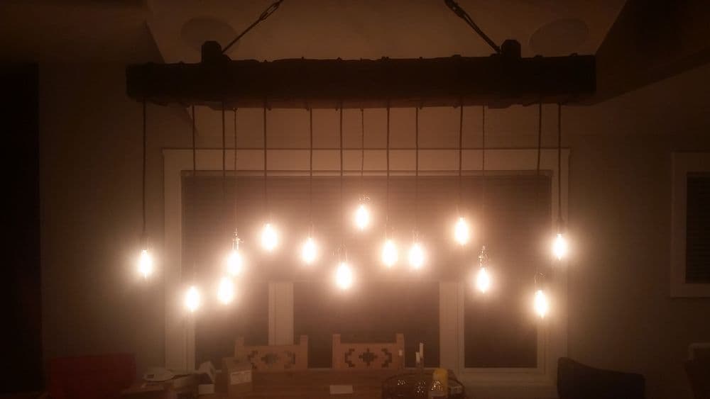 Modern pendant lighting with multiple exposed bulbs hanging over a wooden dining table.
