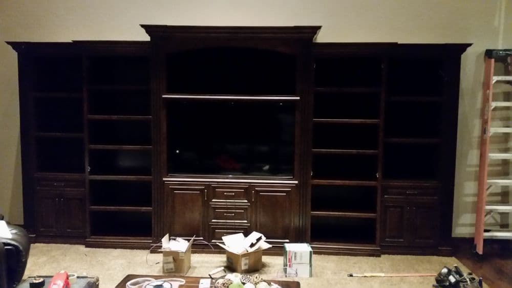 Dark wood entertainment center with shelves and cabinets, empty space for TV, and scattered boxes.