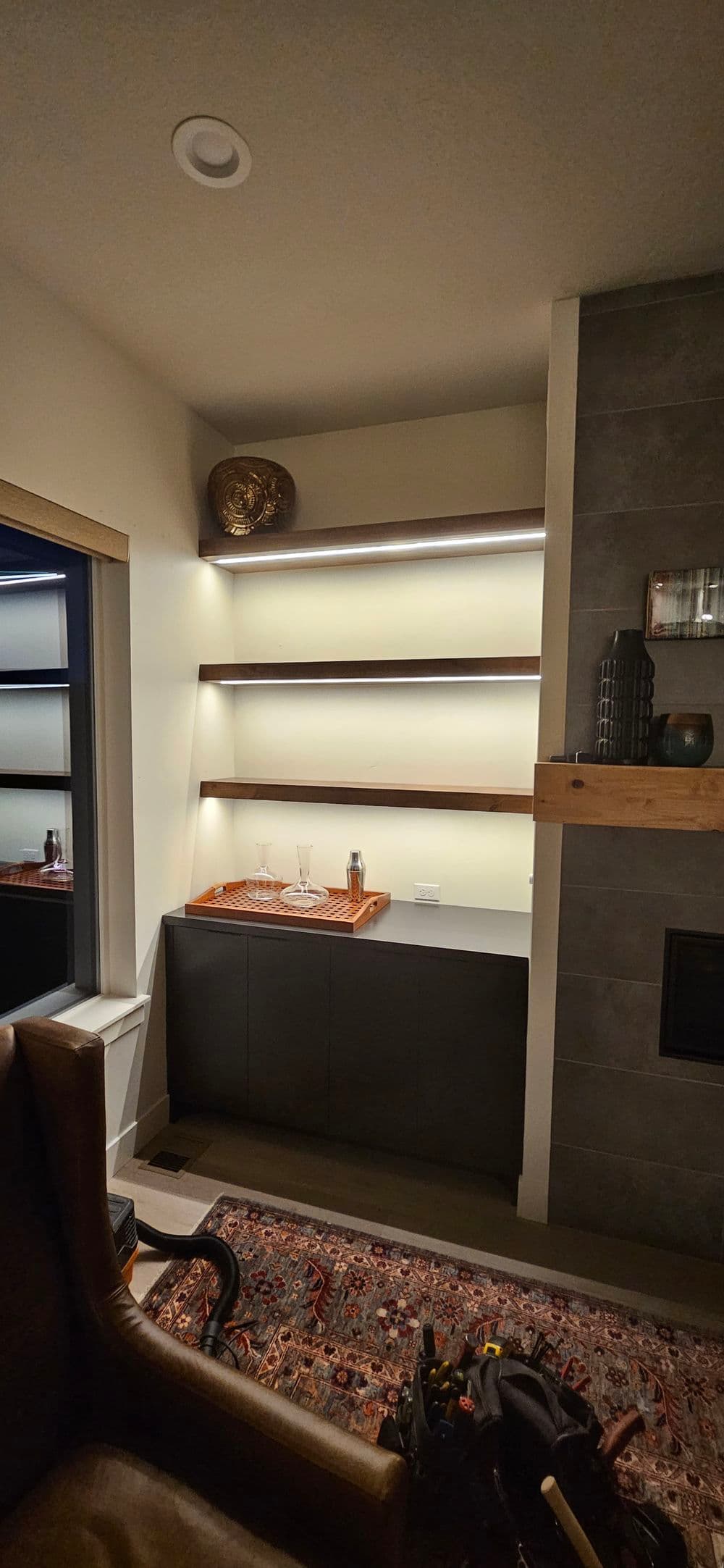 Modern home decor featuring illuminated shelving and a sleek cabinet in a cozy living space.