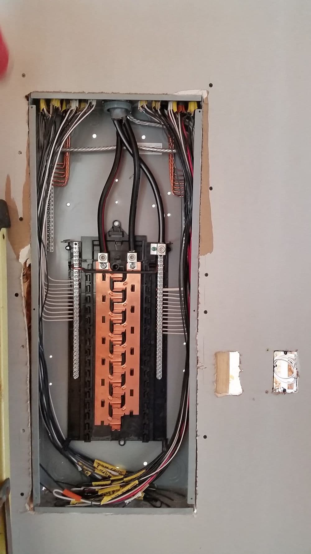 Residential electrical panel with circuits and wiring inside a wall.