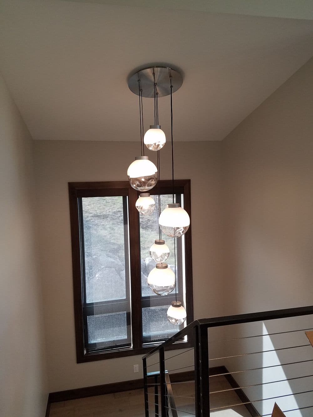 Modern pendant lighting fixture in a stairwell with large windows. Bright and stylish design.