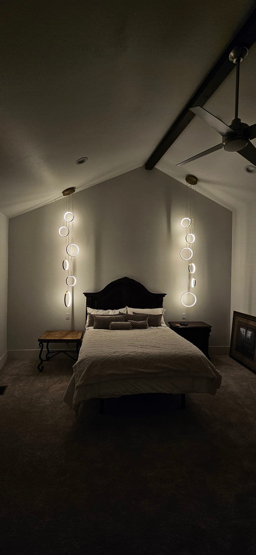 Cozy bedroom with modern lighting, plush bed, and stylish decor on walls.