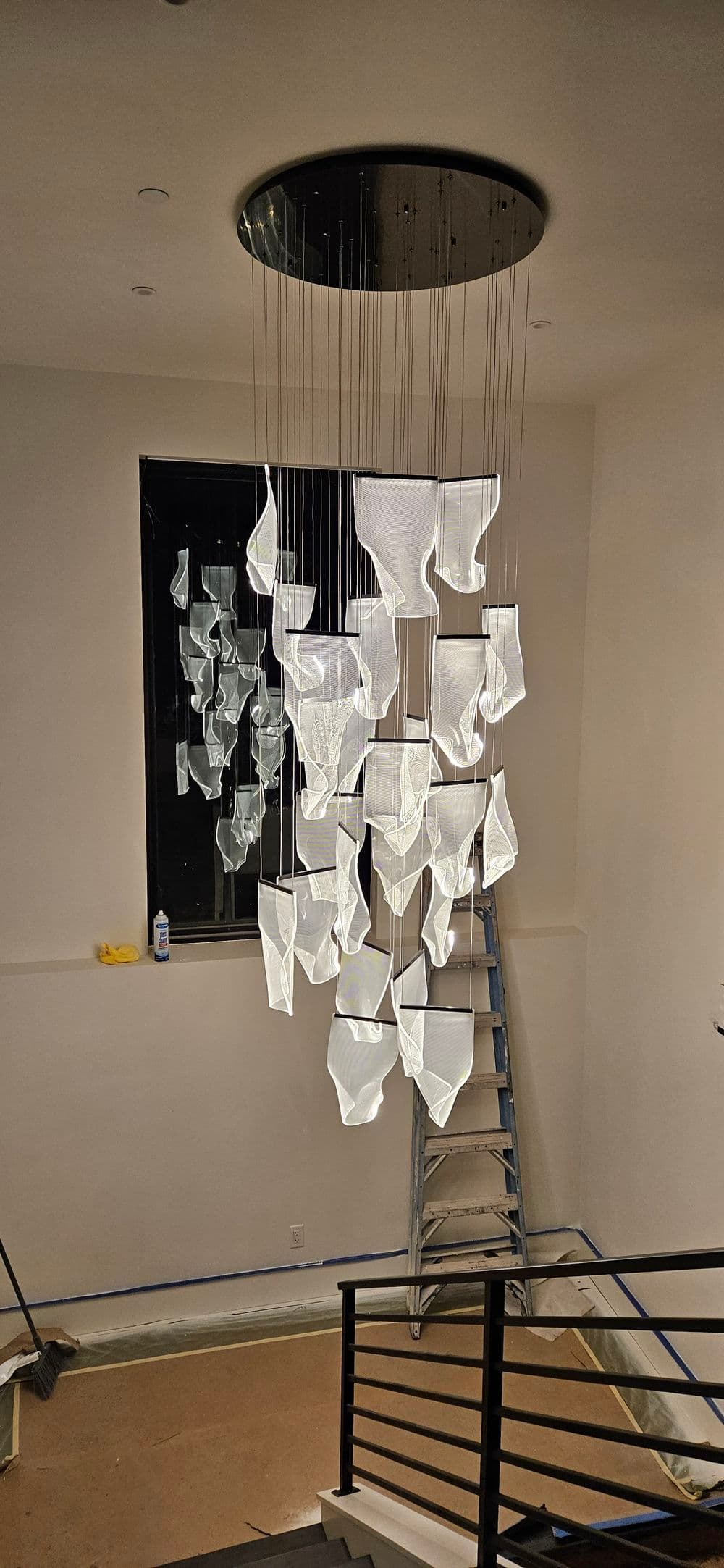 Modern chandelier design featuring abstract glass shapes, illuminating a stairwell.