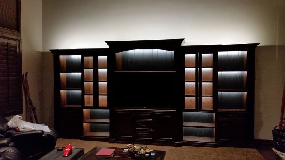 Dark wooden entertainment center with built-in shelves and ambient lighting.
