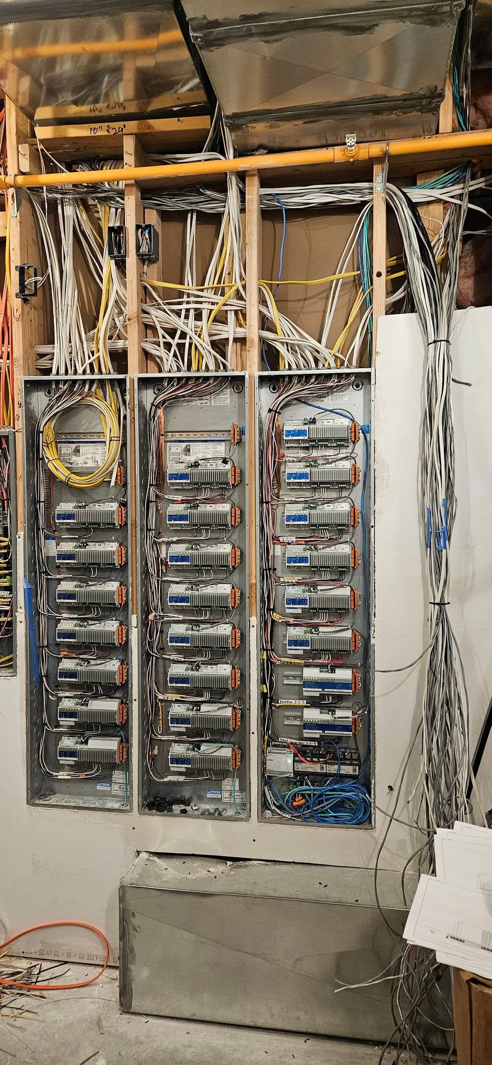 Wired wall panel with multiple electrical modules and tangled cables in a technology installation.