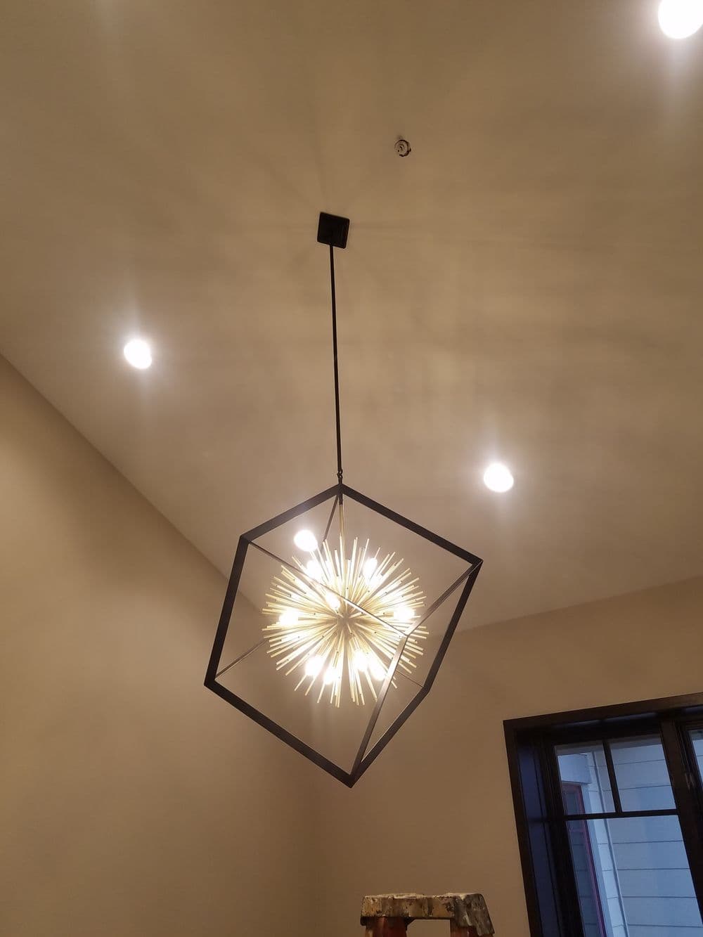 Modern geometric pendant light with starburst design hung from ceiling in a stylish room.
