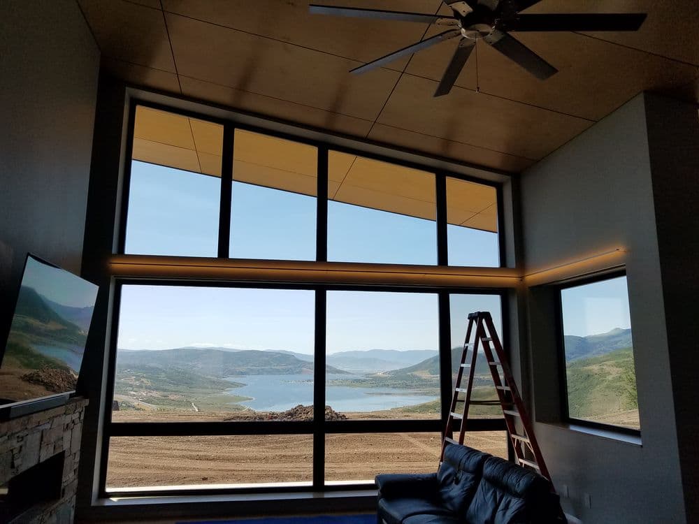 Modern living room with large windows showcasing a scenic lake and mountain view.