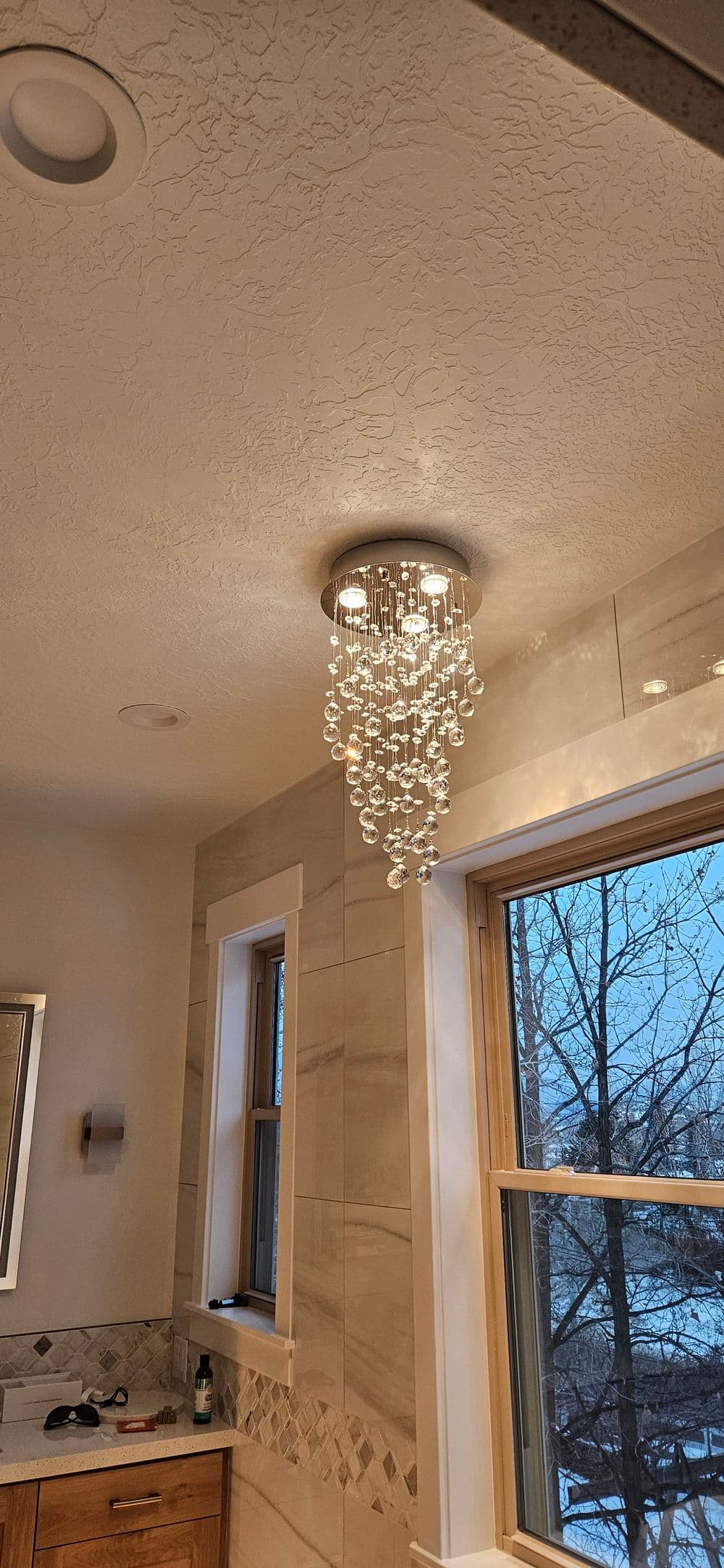 Modern bathroom featuring a glass chandelier and window with a winter view.