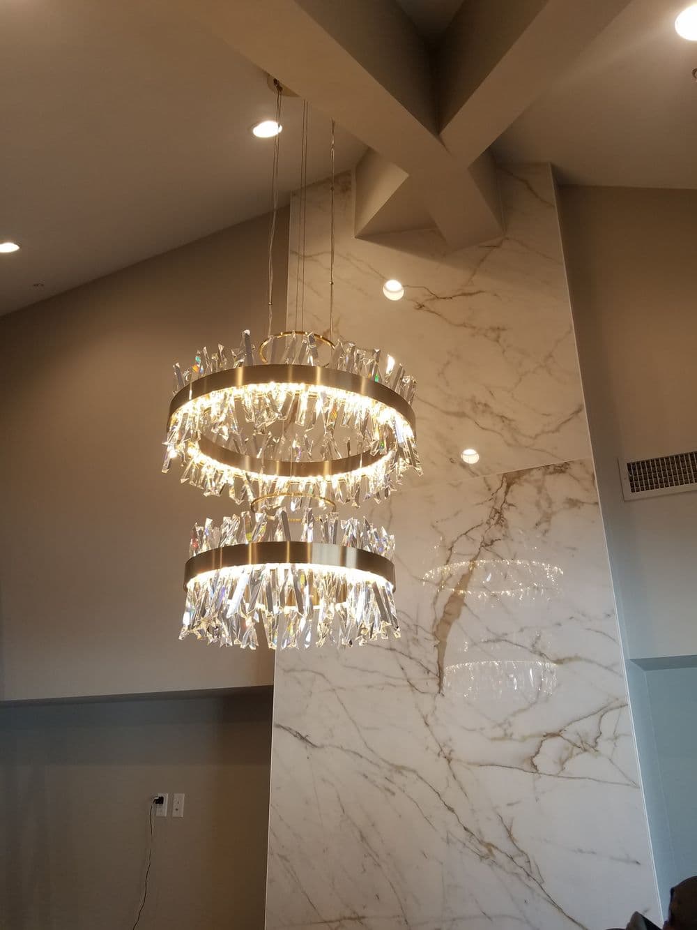 Modern chandelier with crystal-like accents, illuminated, hanging in a stylish interior.