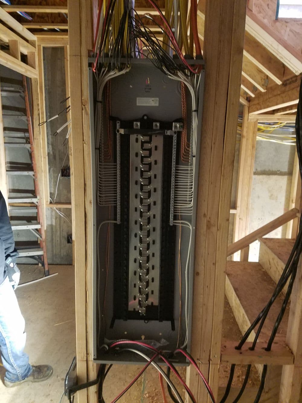Electrical panel installation with numerous wires in a residential construction site.
