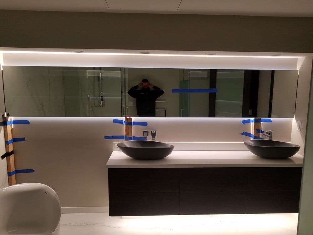 Modern bathroom with dual sinks and a backlit mirror, featuring blue painter's tape detail.