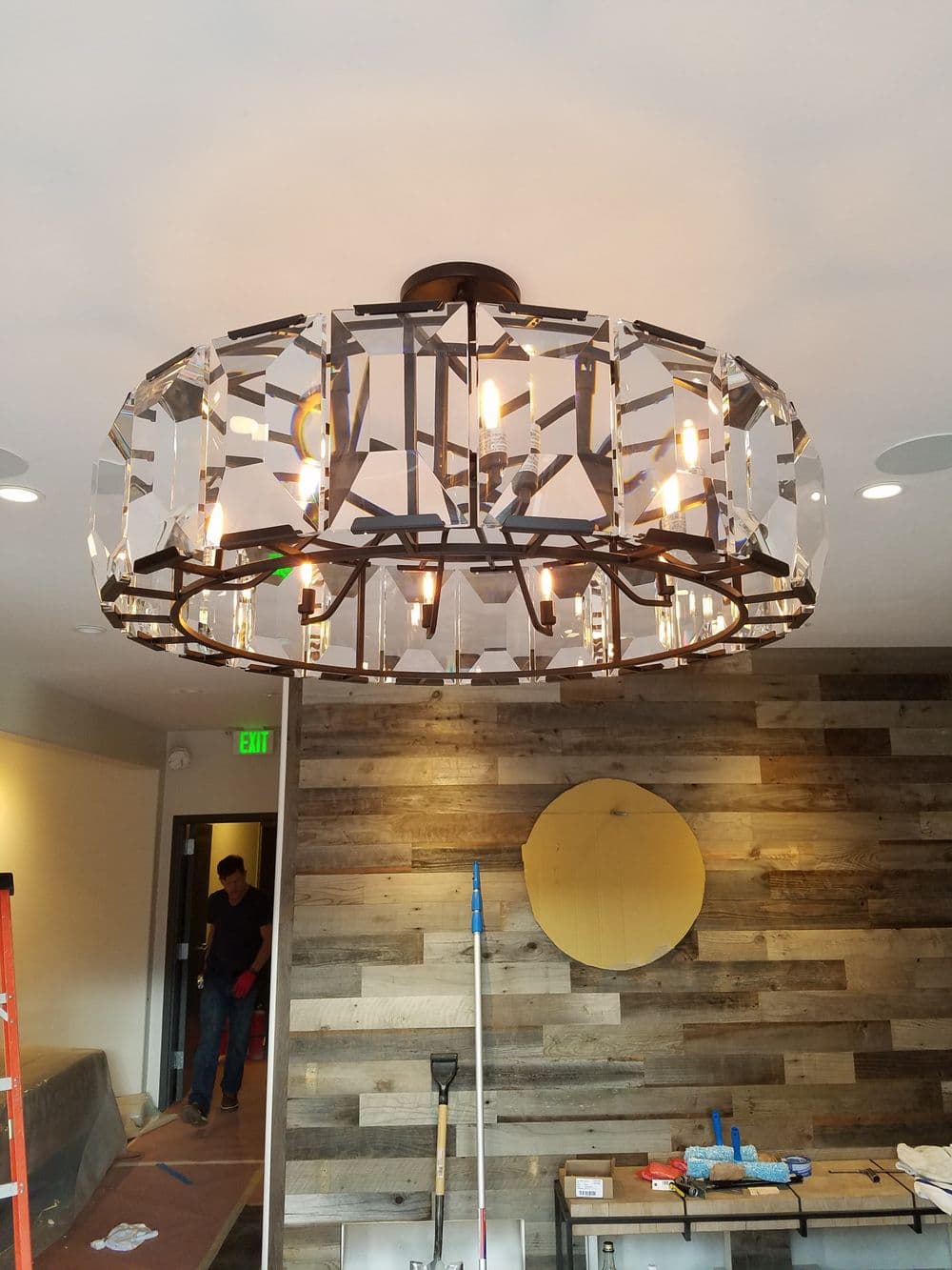 Modern chandelier with crystal design and exposed bulbs, illuminating a stylish interior space.