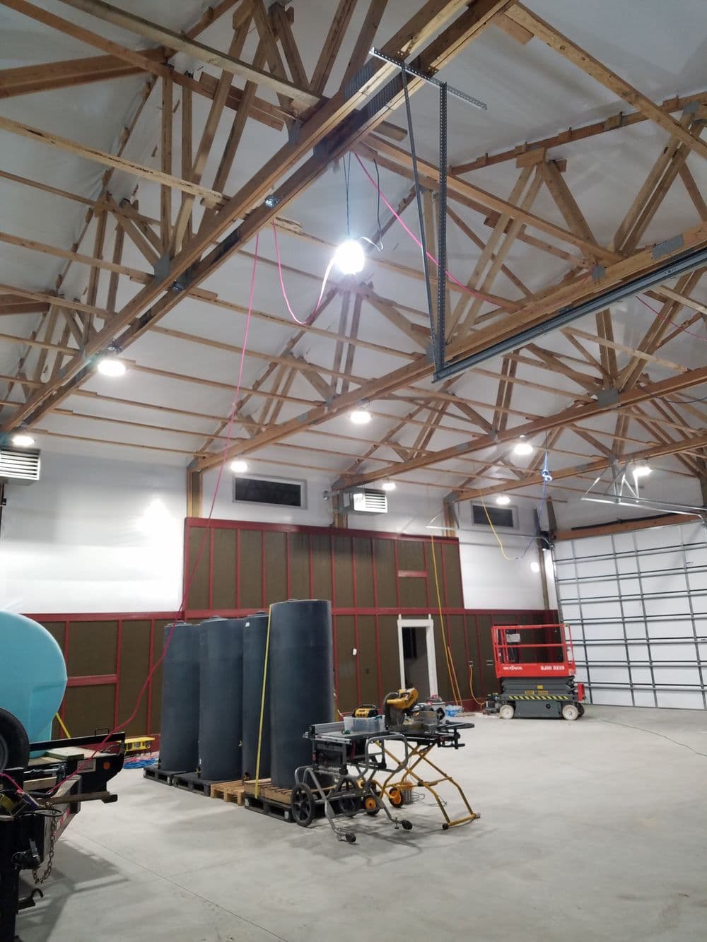 Interior of a spacious workshop with wooden beams, machinery, and storage barrels.