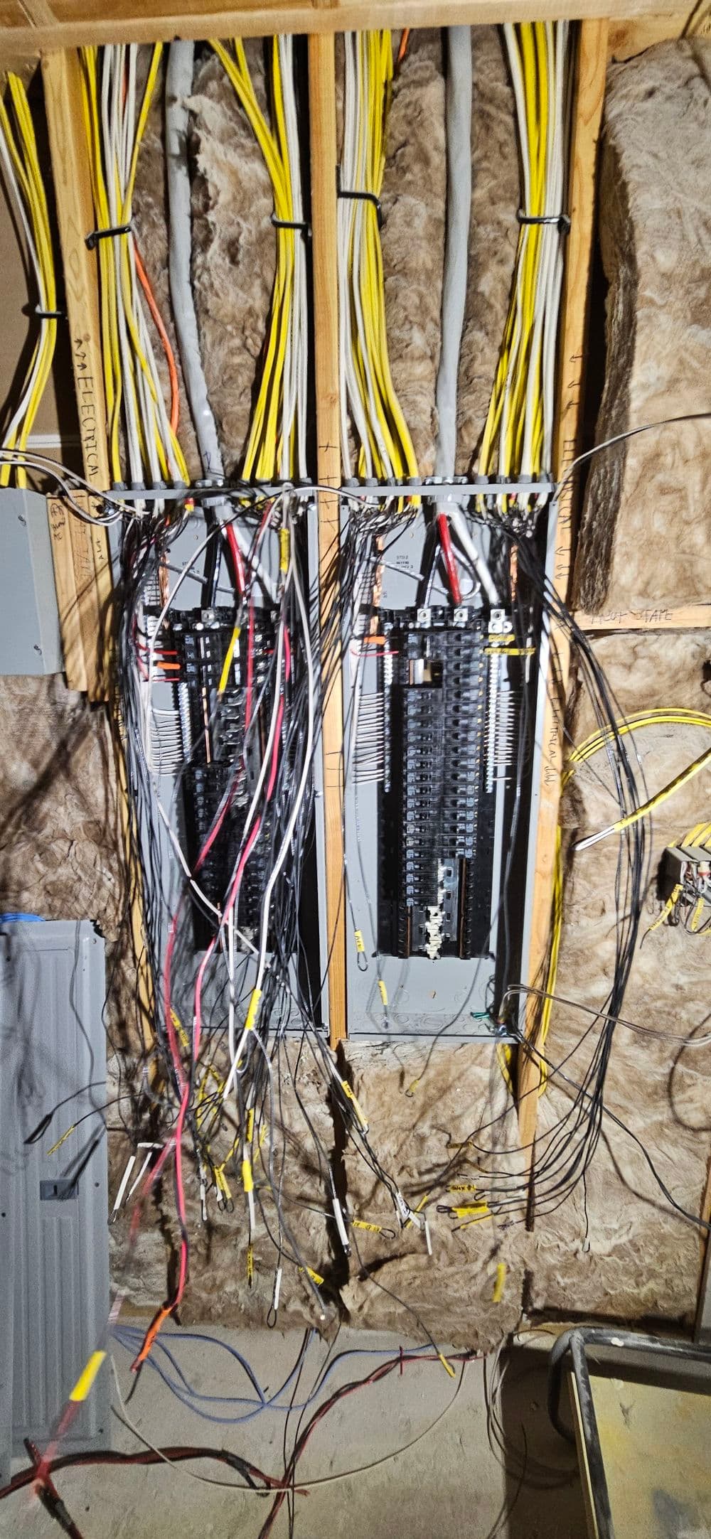 Wiring panels with numerous electrical wires in an insulated basement.
