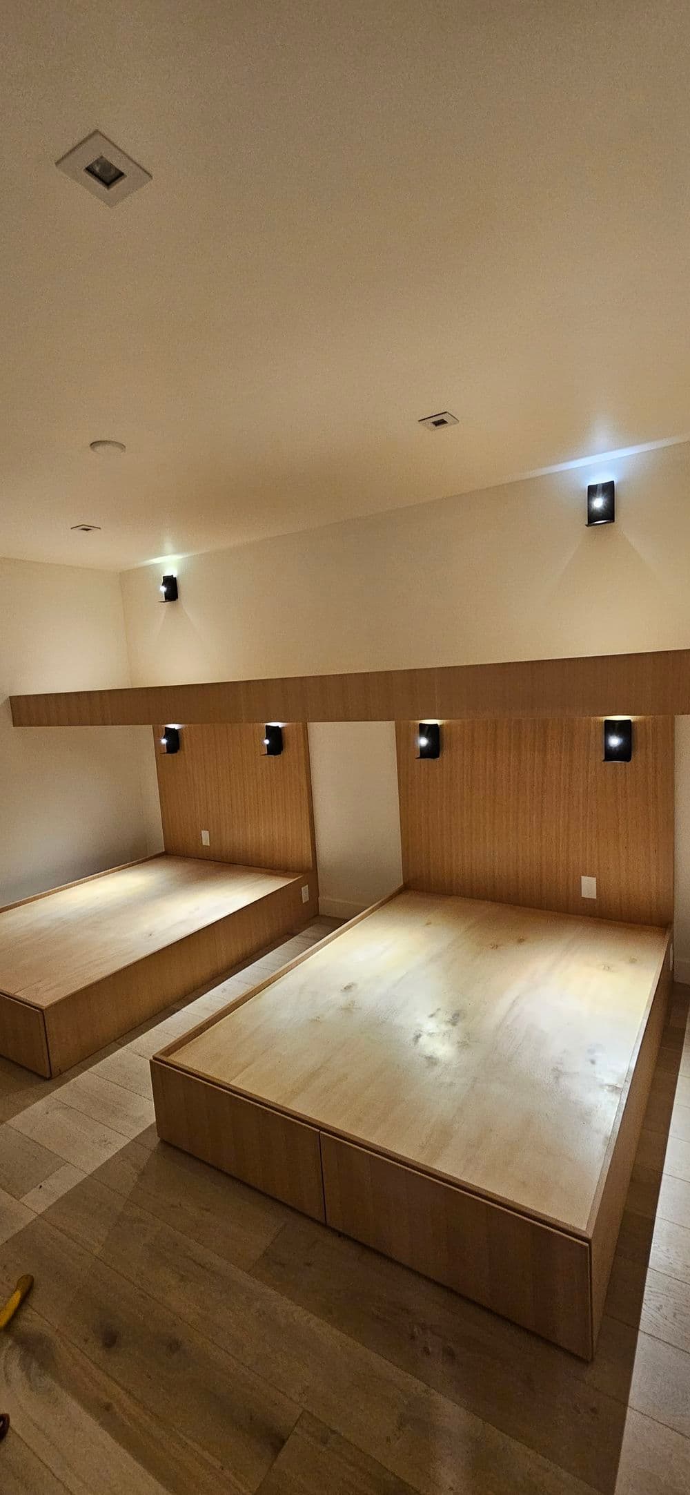 Minimalist bedroom design with wooden beds and soft lighting, creating a cozy atmosphere.