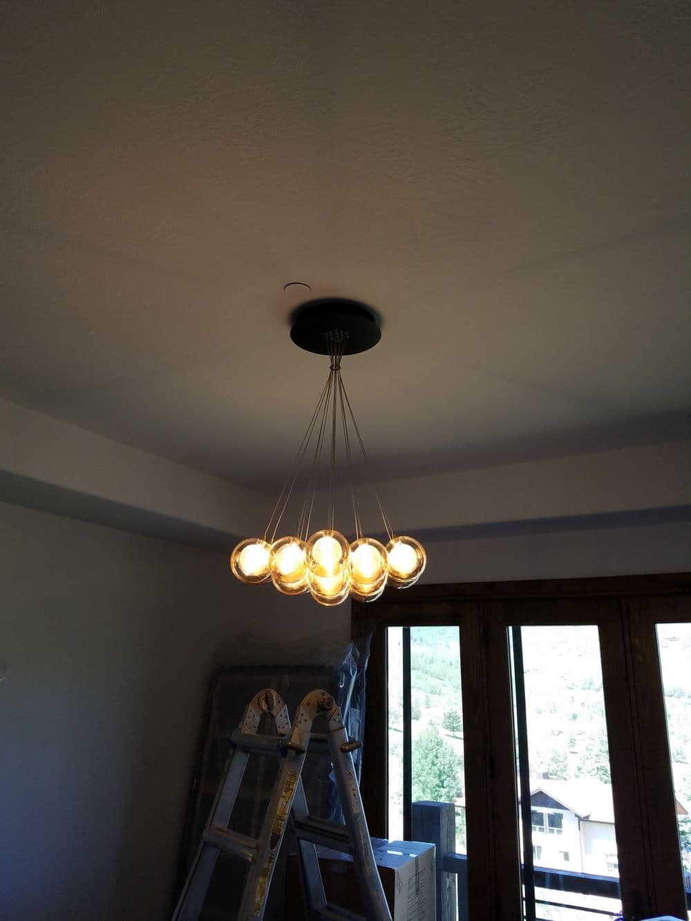 Modern pendant light fixture with eight globe bulbs, hanging from a black ceiling mount.
