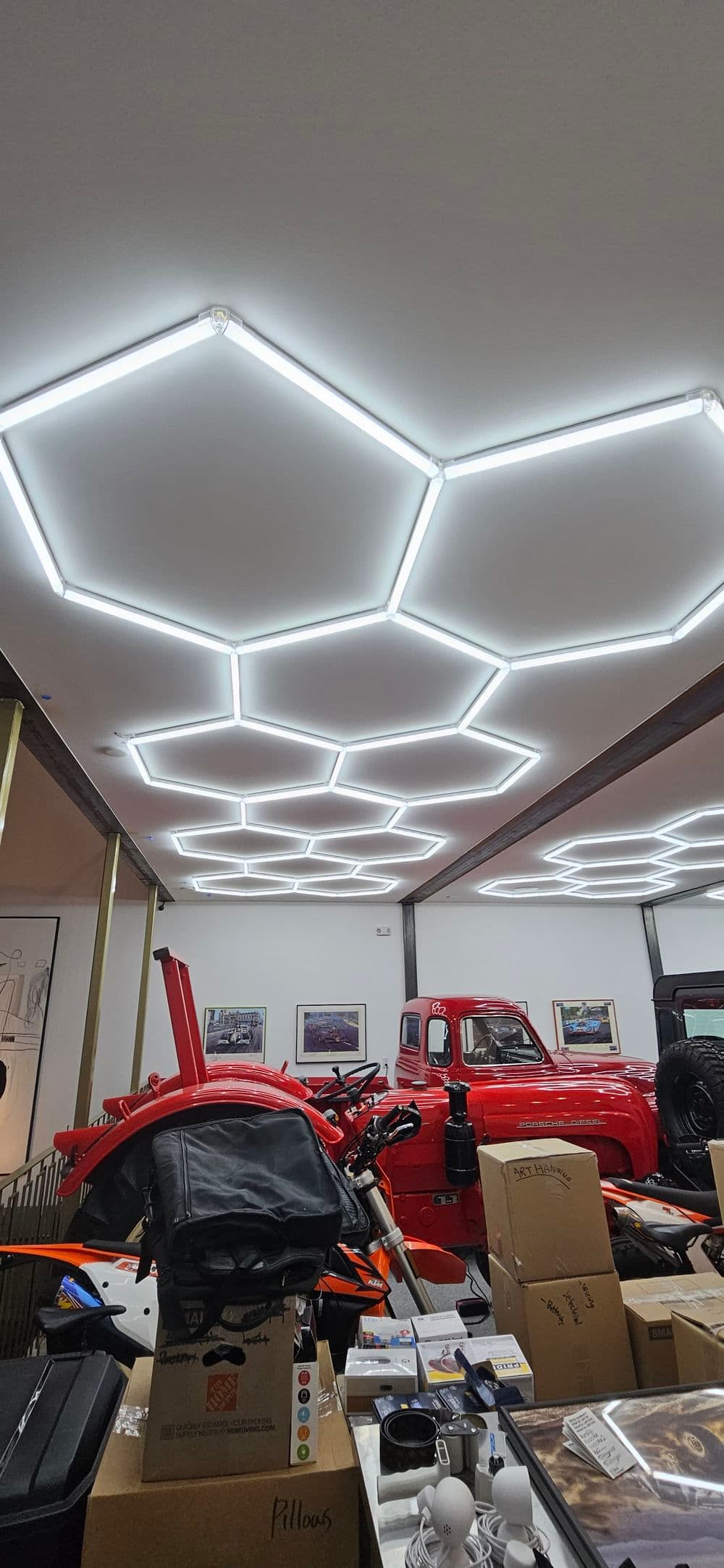 Modern hexagonal LED ceiling lights illuminate a garage filled with vehicles and decor items.