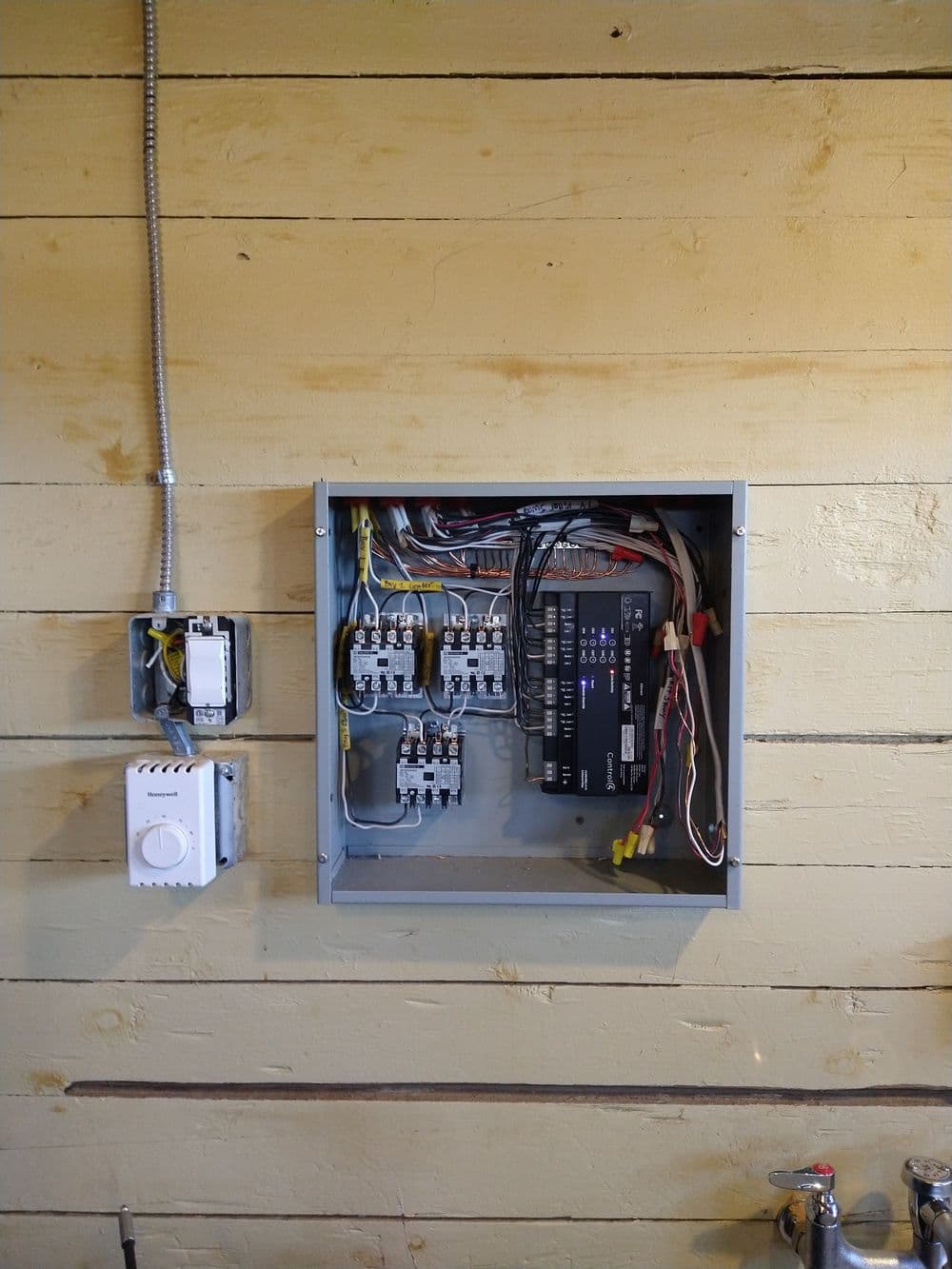 Electrical panel installation on a wooden wall with labeled circuit breakers and wiring.