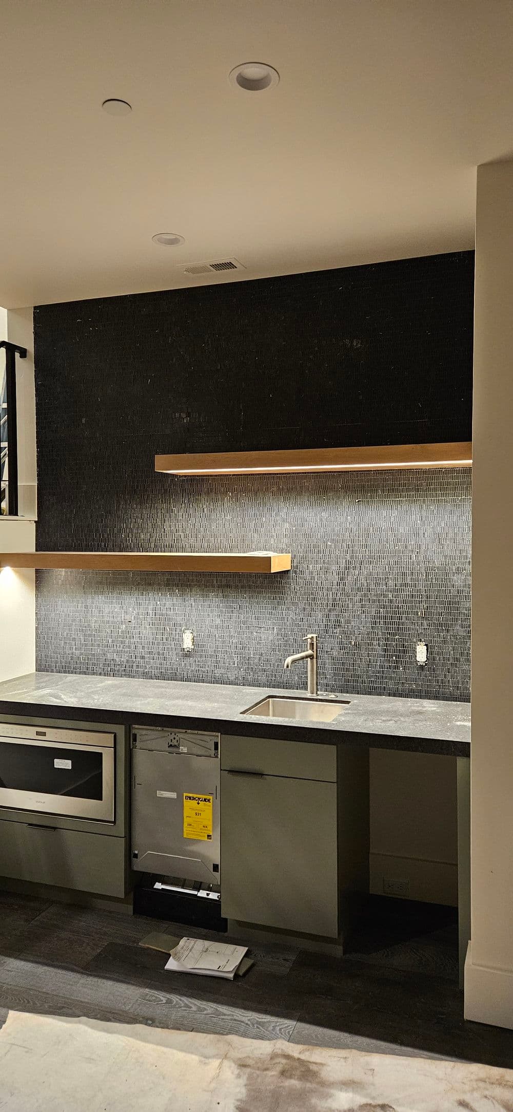 Modern kitchen featuring black backsplash, wooden shelves, and sleek appliances.